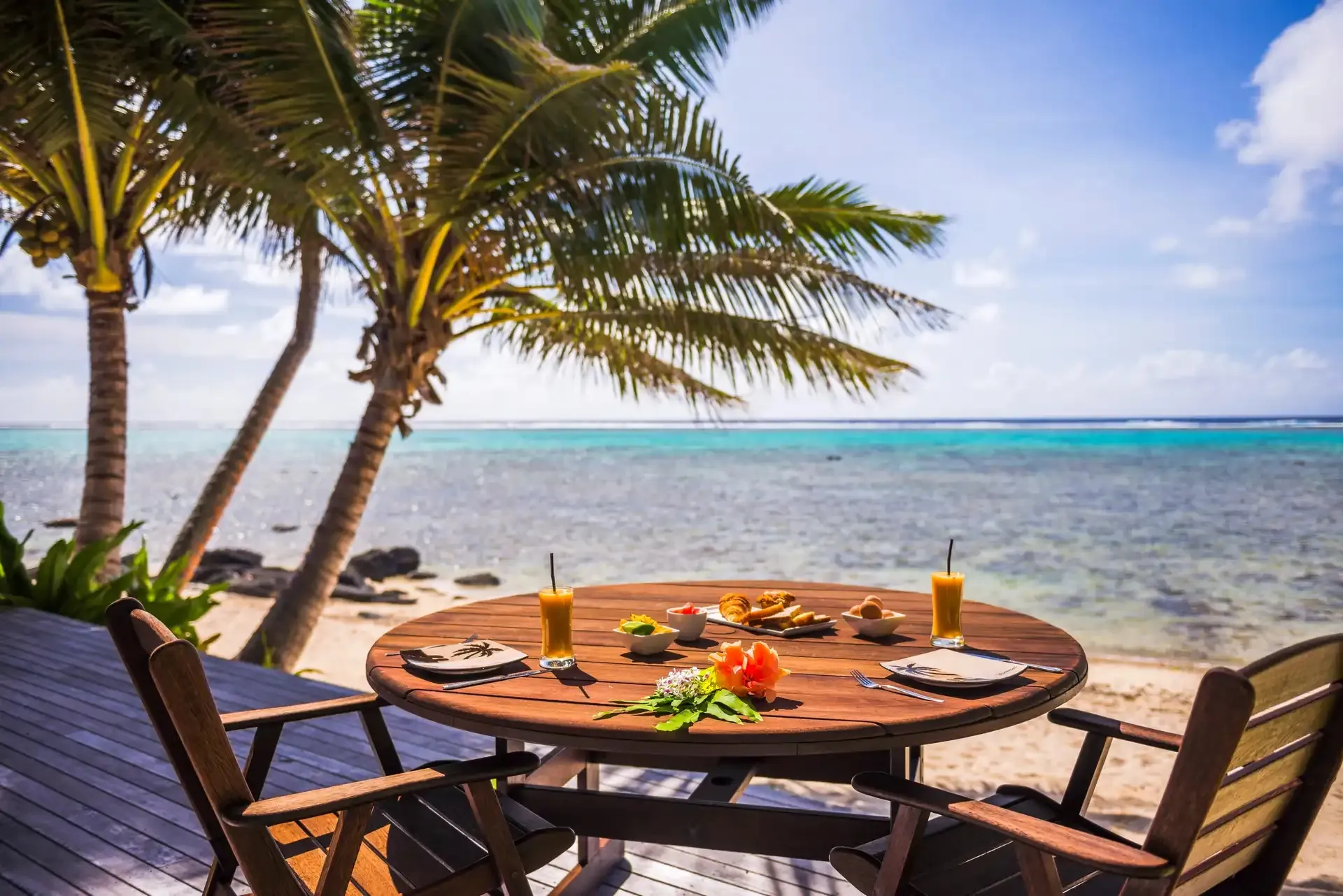 Lange runde Tafel für ein Familienessen auf einem Stranddeck unter Palmen