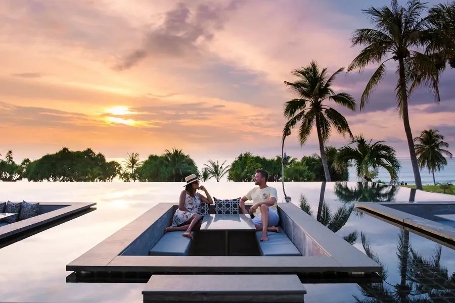 Ein Paar in einer versenkten Lounge neben einem Infinity-Pool bei Sonnenuntergang