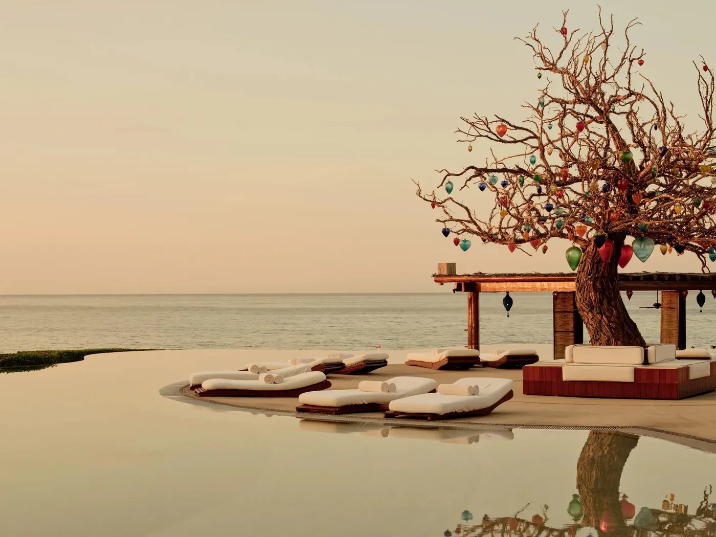 Hauptpool von Rosewood Las Ventanas al Paraíso mit Liegen und einem geschmückten Baum am Meer
